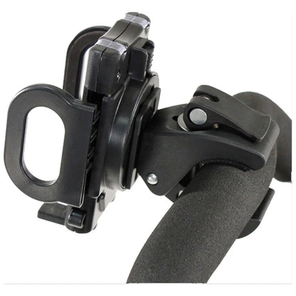 A black device clamps onto a cylindrical handle with a textured grip securing a smartphone or similar object in place for hands-free use in various environments.