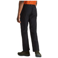 Black pants are worn by a person standing still in outdoor footwear with an orange shirt visible from the front in a neutral setting suggesting a casual or active environment.