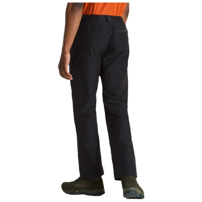 Black pants are worn by a person standing still in outdoor footwear with an orange shirt visible from the front in a neutral setting suggesting a casual or active environment.