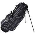 A black and grey golf bag with a logo stands upright on two retractable legs showcasing its padded shoulder strap and multiple zippered pockets for carrying golf equipment.