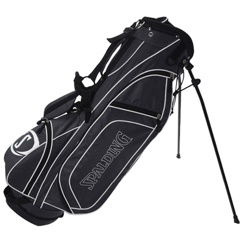 A black and grey golf bag with a logo stands upright on two retractable legs showcasing its padded shoulder strap and multiple zippered pockets for carrying golf equipment.