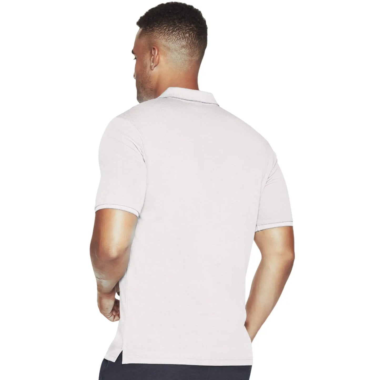 A man is standing with his back to the viewer wearing a light-colored polo shirt with short sleeves and a collar in a simple white background setting.