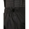 Black athletic shorts with an adjustable drawstring are being showcased close-up on a person wearing a textured gray top in an indoor setting.