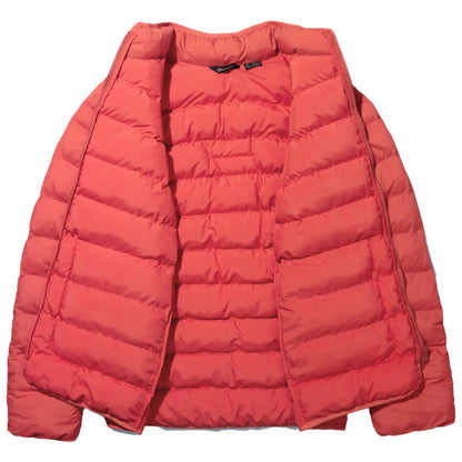 A coral puffer jacket is displayed open with its interior showing the quilted design and the zipper on one side is unfastened in a neutral background.