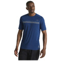 A man stands confidently wearing a fitted blue athletic t-shirt with a dotted design across the chest and black shorts against a plain white background.