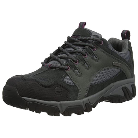 A dark green hiking shoe features a combination of suede and mesh materials with thick rubber soles and prominent laces designed for outdoor activities in a natural environment.