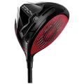 A golf driver with a sleek black and red design rests vertically, featuring a large clubhead and textured striking surface, ready for use on a golf course.
