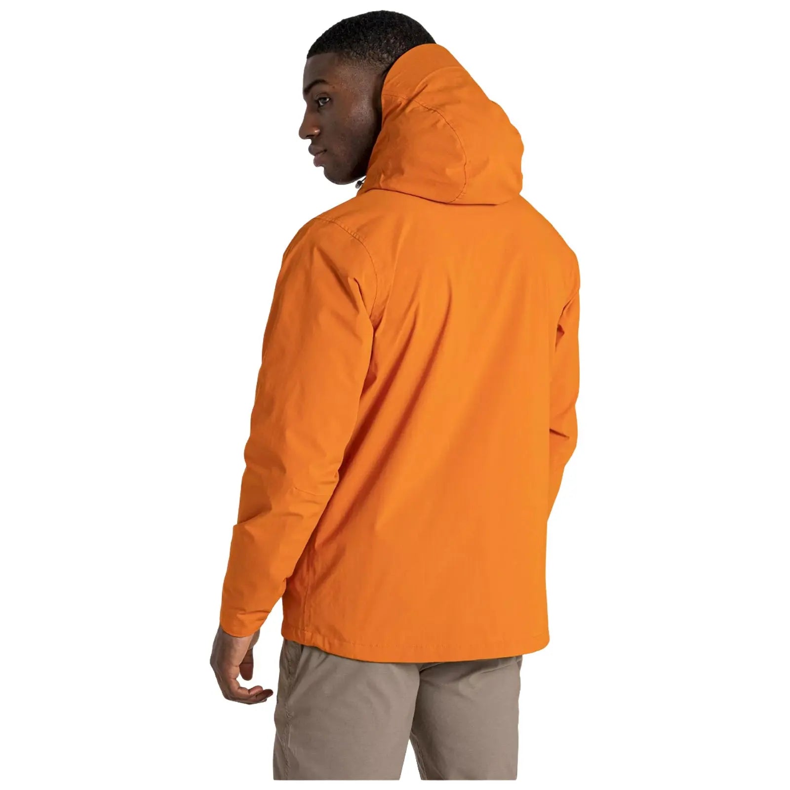 A person wearing an orange hooded jacket stands with their back turned, looking slightly over their shoulder in a minimalist setting with a plain white background.