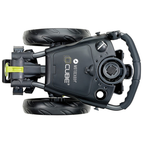 A compact black golf push cart with two large wheels is positioned upside down revealing its handle and controls designed for easy maneuvering in various terrains.