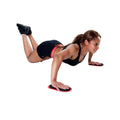 A woman performs push-ups using fitness sliders in a workout pose. She is concentrated and positioned on a plain background, wearing athletic clothing that enhances her mobility.