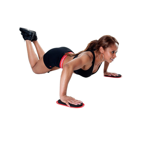 A woman performs push-ups using fitness sliders in a workout pose. She is concentrated and positioned on a plain background, wearing athletic clothing that enhances her mobility.