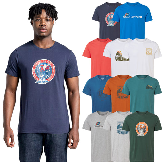 A man stands wearing a navy t-shirt featuring a logo with the text Outdoor Calling Go Explore against a backdrop of various other colorful t-shirts displayed alongside him.