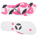 A pair of flip-flops displays a colorful design featuring pink and black floral patterns on a white background while the underside has a textured surface with circular indentations for grip.