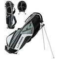 A golf bag stands upright on silver legs showing a sleek black and white design with multiple zippered compartments highlighting a circular top for club storage set against a plain background.