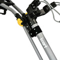 A gray metal frame with a yellow release button and black plastic components holds a cable system, designed for maneuvering, likely part of a cart or support device in a functional setting.