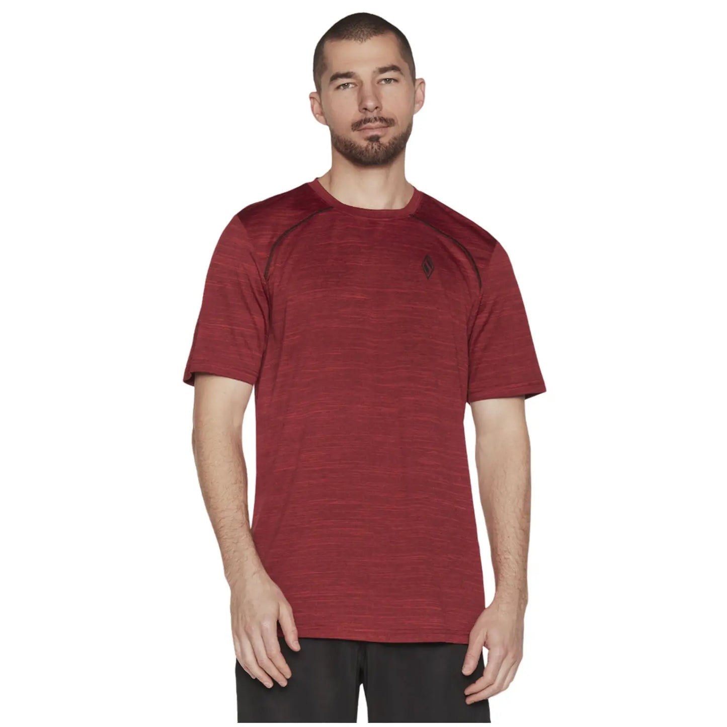 A man stands wearing a red athletic shirt with short sleeves and a logo on the chest. He has a neutral expression and is posed against a plain white background.