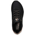 A black sneaker with perforated design and bronze accents sits against a plain background showcasing a sleek silhouette and thick laces highlighting its sporty appearance and cushioning features