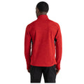 A person is wearing a red long-sleeve top with a high collar in a neutral setting facing away from the viewer, showcasing the garment's design and color against a plain background.