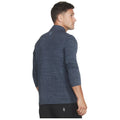 A man is wearing a dark navy long-sleeve athletic shirt with a high collar and looks over his shoulder revealing a stylish and casual appearance in a neutral setting.
