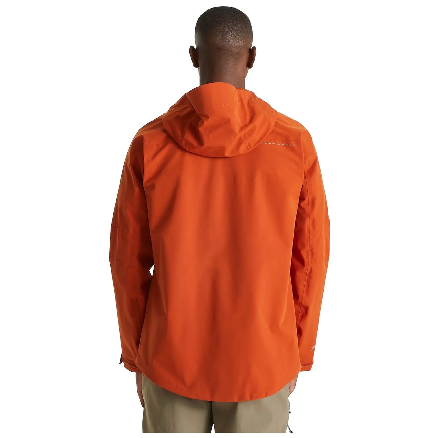 A person stands facing away wearing an orange hooded jacket with a smooth texture in a minimalistic setting highlighting the vivid color against a plain background.
