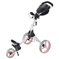 A golf push cart with a white frame and pink wheels is standing upright. It features a handle at the top and a compartment for holding golf equipment.