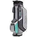 A golf bag stands upright featuring a grey and light blue design with multiple zippered compartments and a strap for carrying in an outdoor golfing environment.