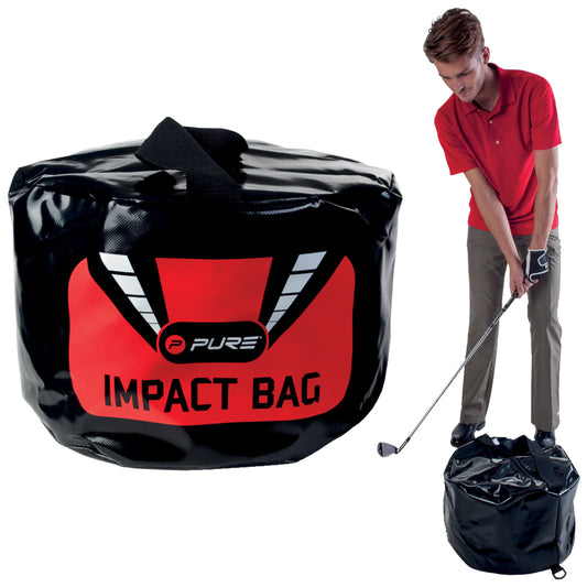 A large black impact bag with red and white branding stands on the ground as a man in a red shirt and gloves prepares to strike it with a golf club.
