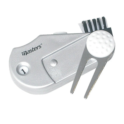A silver golf tool features a brush and a small forked end for cleaning equipment and maintaining course conditions placed against a neutral background