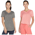 Two women are wearing athletic shirts, one gray and one light pink, smiling in a studio setting showcasing comfortable casual wear. The background is plain and neutral.