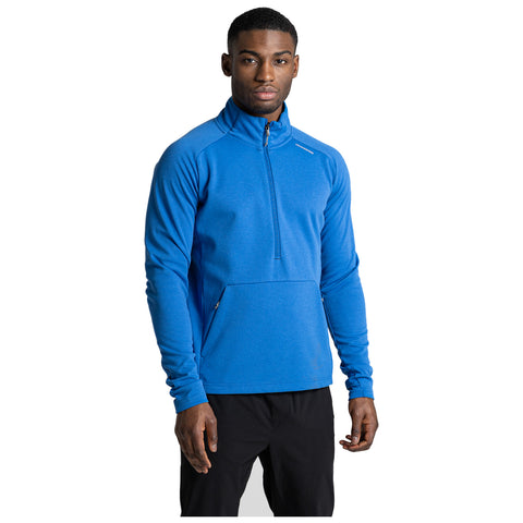 A man stands confidently wearing a bright blue long-sleeve pullover with a zippered collar and front pocket. He is in a neutral background that highlights his attire.
