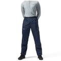 A person stands upright wearing a long-sleeved gray top and navy waterproof pants with a waistband. The scene is neutral and focused on the attire suitable for outdoor activities.
