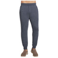 Gray jogger pants are displayed standing upright with an elastic waistband and fitted cuffs. They are worn with light brown slip-on shoes in a neutral environment.