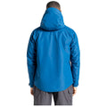 A man is wearing a bright blue waterproof jacket with a hood while facing away from the viewer in an undefined outdoor setting with natural light.