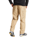 A person is standing with their back to the viewer wearing khaki cargo pants and gray athletic shoes the setting appears to be indoors with a plain background