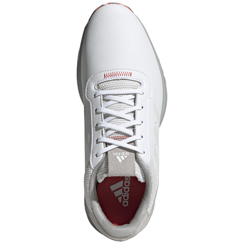 A white athletic shoe with a smooth leather surface and a gray and red inner lining is displayed from an overhead perspective highlighting the laces and branding.