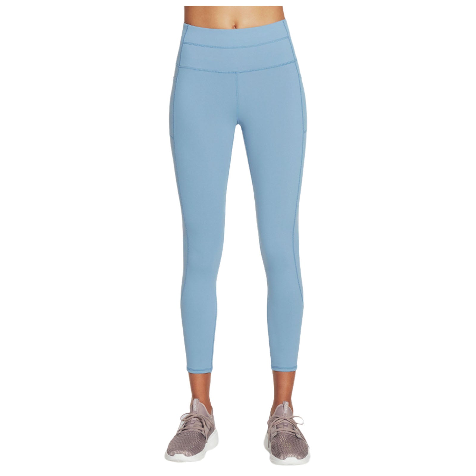 Light blue leggings are worn by a person standing upright wearing light beige athletic shoes in a neutral space focused on activewear.