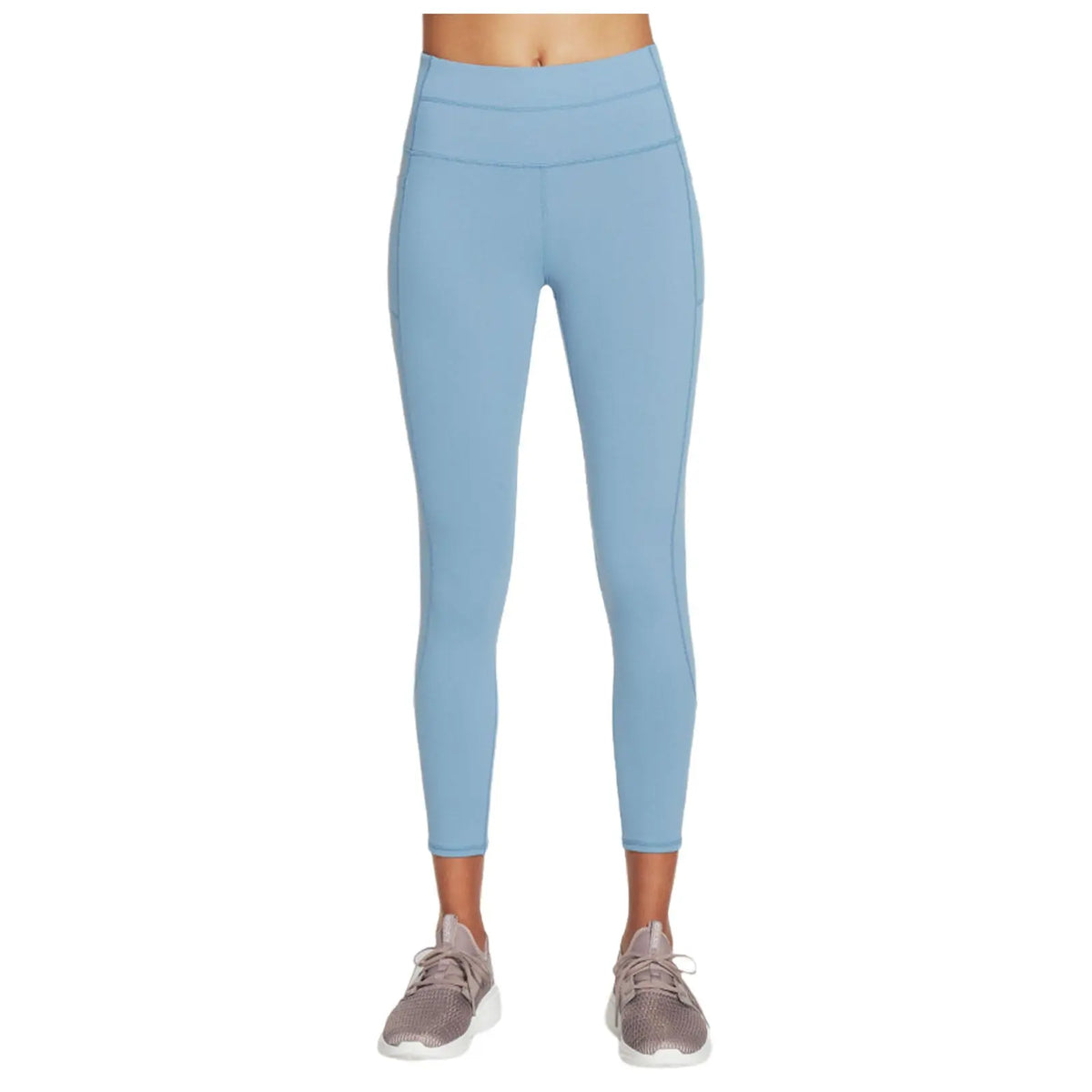 Light blue leggings are worn by a person standing upright wearing light beige athletic shoes in a neutral space focused on activewear.
