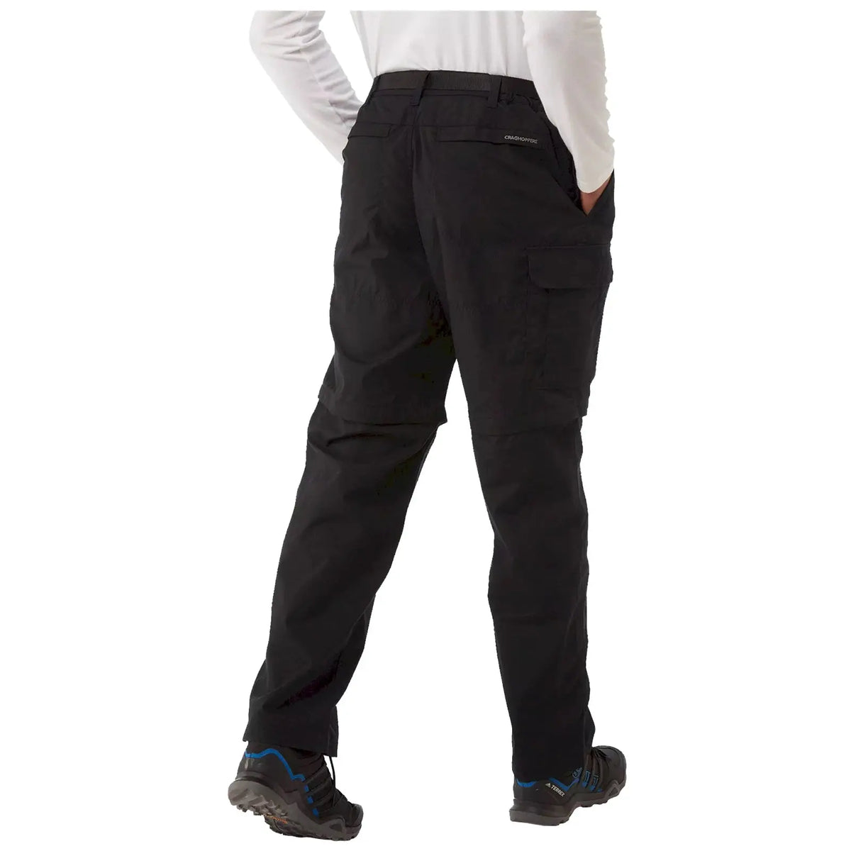 Black cargo pants are worn by a person standing with their back facing the viewer hands in pockets in a casual outdoor setting the pants have pockets at the sides and back