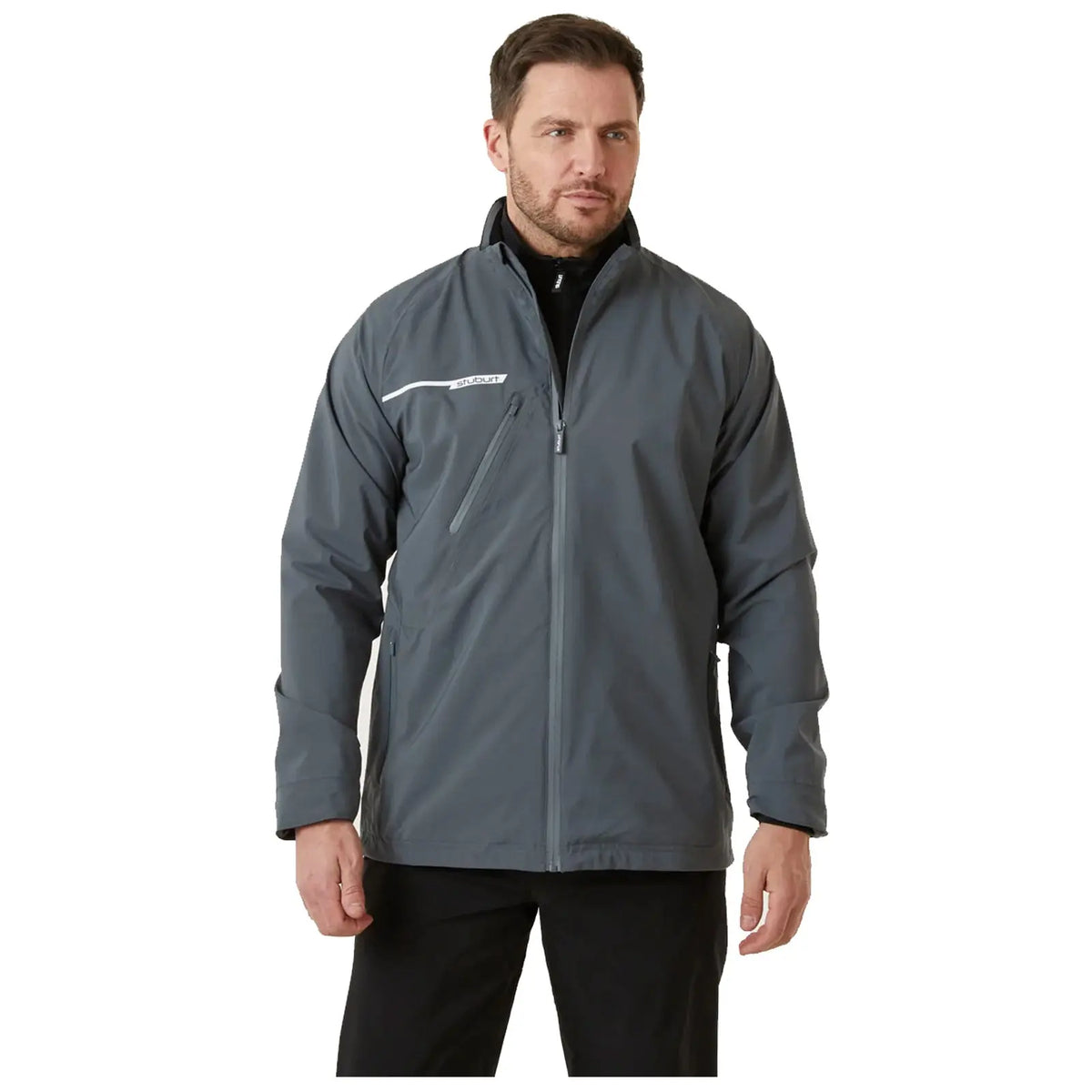 A man stands wearing a gray jacket with a white stripe and a zippered pocket the context suggests he is in a neutral indoor setting with plain background lighting