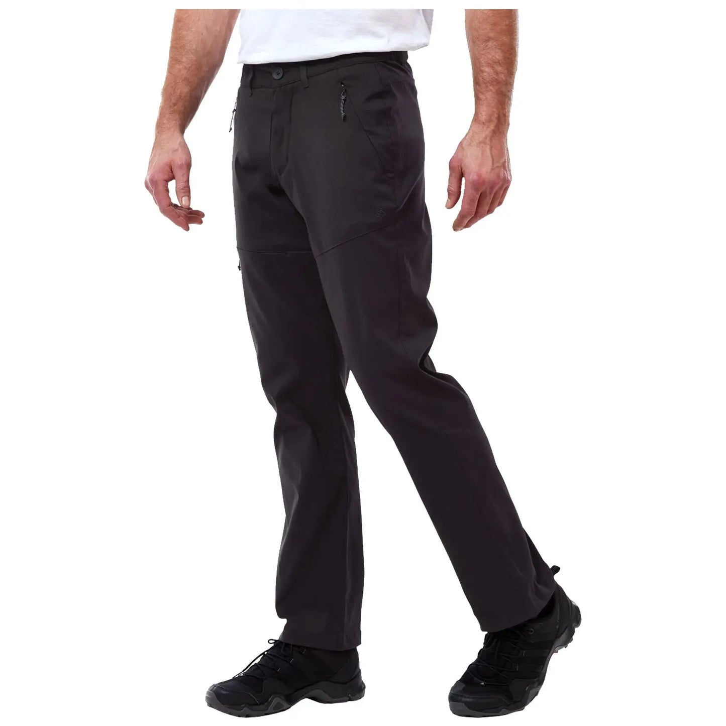 Craghoppers Mens Kiwi Pro II Walking Trousers Black pants with a modern design are being worn by a person who is standing and slightly bending one knee while wearing black athletic shoes in a neutral background.