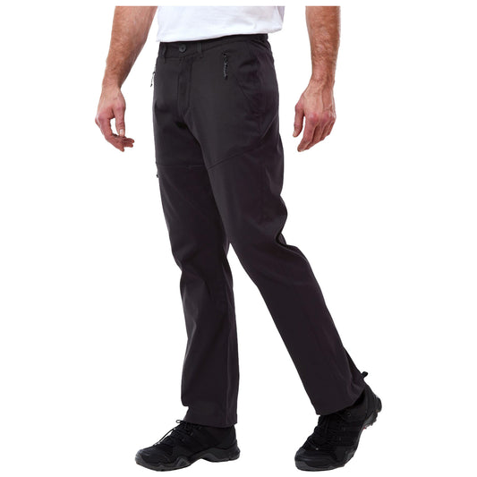 Craghoppers Mens Kiwi Pro II Walking Trousers Black pants with a modern design are being worn by a person who is standing and slightly bending one knee while wearing black athletic shoes in a neutral background.