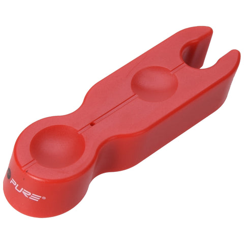 A red plastic tool sits on a flat surface designed to hold two small circular objects it has a forked end for gripping or lifting items in close proximity.