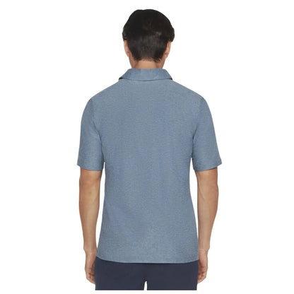 A person is facing away wearing a blue short-sleeved polo shirt in a neutral background that emphasizes the shirt's texture and style