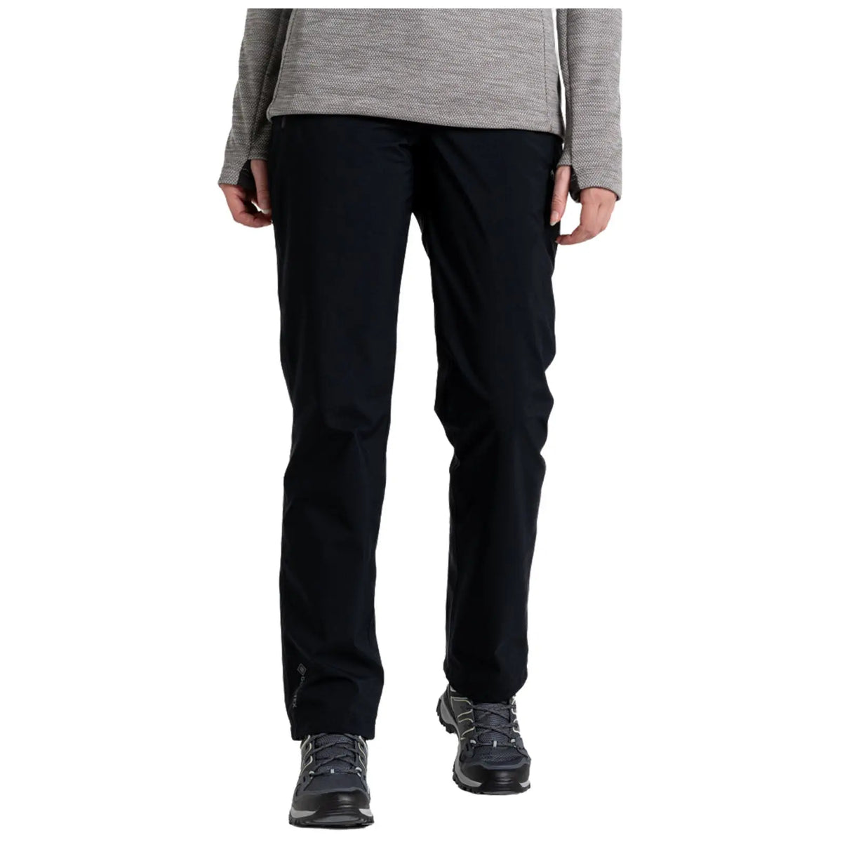 Black pants are being worn by a person who is standing upright with both hands visible near their waist in a neutral indoor setting with a plain background.