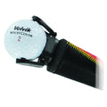 A golf ball labeled Volvik WhiteColor 2 rests in a holder attached to a golf club with a textured grip featuring vibrant stitching, suggesting preparation for a game on a green course.