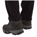 Hiking boots are positioned on a surface with the pant cuffs slightly rolled up revealing the boots designed for outdoor activities in a rugged environment.