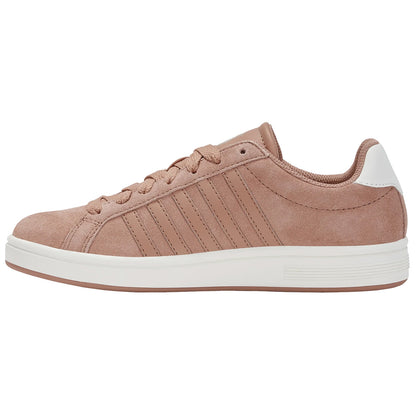 A pink suede sneaker features a white heel and is adorned with three vertical stripes on the side resting on a white rubber sole against a plain background.