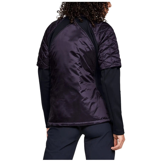 A person wearing a black long-sleeve shirt and a quilted purple jacket with short sleeves stands with their back partially visible in a neutral background.