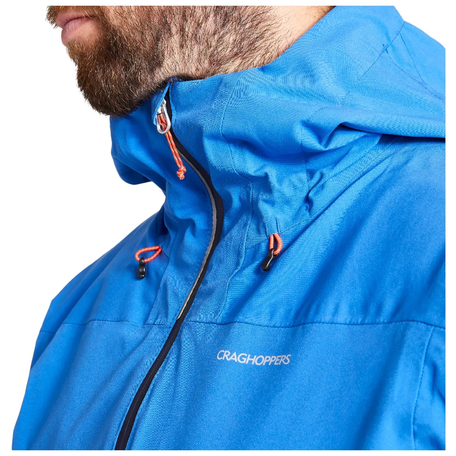 A blue jacket with an adjustable hood is worn by a person showcasing its zippers and drawstrings in a close-up view against a plain background