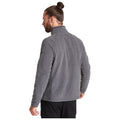 A man wearing a gray fleece jacket stands with his back to the viewer his hair is pulled into a bun the setting appears neutral with no specific context provided.